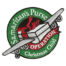 A present with airplane wings flies through a wreath that says Samaritan's Purse Operation Christmas Child.